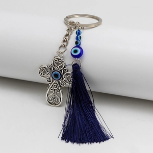 Detail of silver cross tassel keychain with blue evil eye beads and long silk fringe