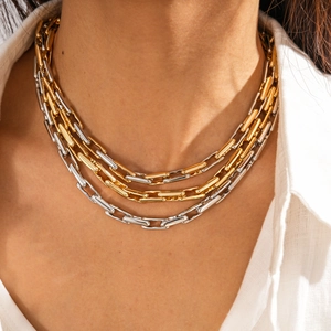 Macro shot of layered gold and silver chain necklace on neck with polished metal links