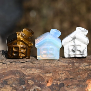 Close-up of small house-shaped natural crystal carvings in tiger eye and opal gemstones