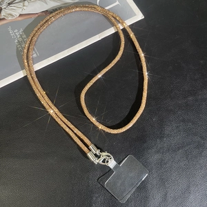 Luxury gold rhinestone phone strap with metal clasps and transparent patch on black background
