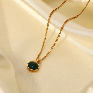 Detail of 18K gold-plated stainless steel chain with green oval stone pendant on silk