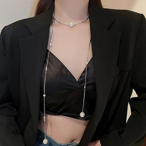 Detail view of a long fringe pearl necklace with silver chains on a black blazer