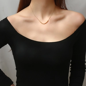 Detail of elegant gold beaded necklace worn by a model on a minimalist black top