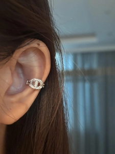 Macro view of silver pig nose ear cuff with inlaid zircons worn on the cartilage ear bone