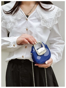 Detail of blue mini patent leather bag with unique silver metal handle and chain strap