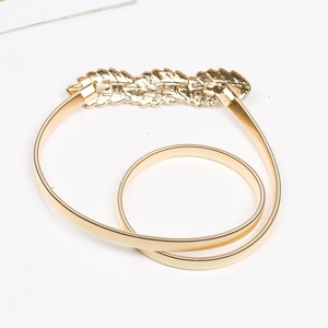 Detail of golden metal spring belt featuring a delicate textured leaf buckle design