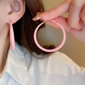 Detail of pink matte acrylic hoop earrings worn by a model for a stylish look