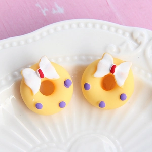 Macro view of yellow matte resin donut charms with white bows for DIY phone case decor
