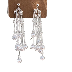 Elegant long silver tassel earrings with white pearls hanging on a display card