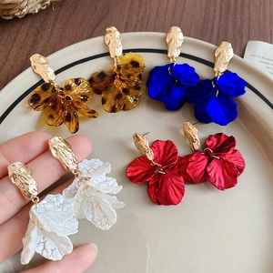 Detail of layered petal tassel earrings in amber leopard, blue, red, and white finishes