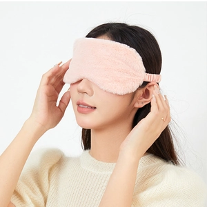 Close-up of a soft pink plush sleep mask worn by a model for comfortable light blocking