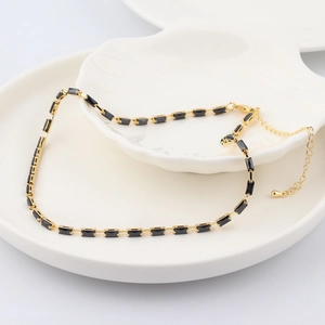 Close-up of black rectangular cubic zirconia on a gold chain necklace in a shell tray