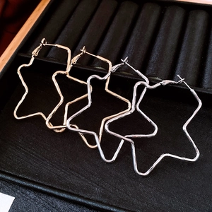 Detailed close-up of minimalist star-shaped metal hoop earrings in gold and silver finish