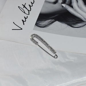 Sparkling silver crystal rhinestone safety pin brooch on elegant white silk background