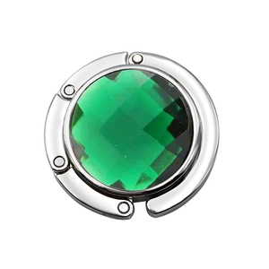 Close-up of portable purse hook with a faceted green gemstone and silver metal finish