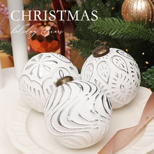 Close-up of white and silver textured Christmas balls with embossed floral patterns on a plate