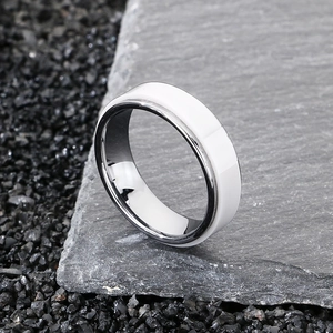 Dettaglio di anello in ceramica bianca e acciaio su sfondo di pietra naturale scura