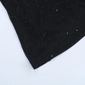 Detail of black sequined fabric showing silver glitter and fine stitching on the evening dress