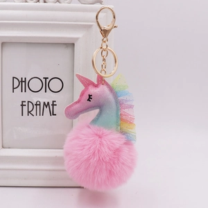 Detailed close-up of a pink unicorn pom-pom keychain with gold metal ring and lobster clasp