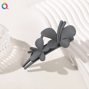 Close-up of a matte dark grey butterfly hair clip on white textured background