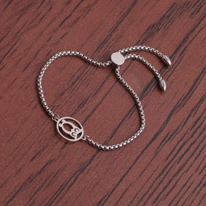 Adjustable stainless steel owl pendant bracelet on a rustic wood background