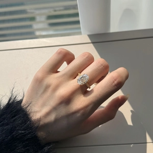 Close-up of a luxury oval cut zircon ring with a textured gold band on a hand