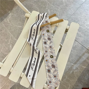 Dettaglio di un foulard in seta beige con motivi floreali e scritte Paris su una sedia