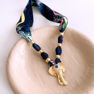 Detailed shot of navy star print scarf necklace with golden elephant pendant and evil eye