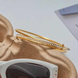 Macro detail of gold plated zircon bangle featuring a luxury interlaced double ring design