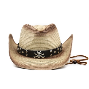 Détail d'un chapeau de paille western avec bande en cuir, emblème de crâne et clous