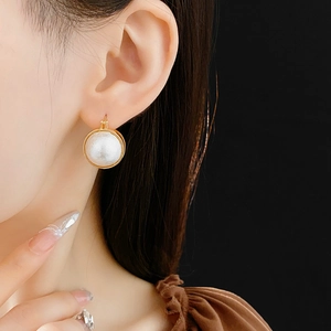 Gros plan de créoles dorées élégantes avec une grande perle ronde blanche sur l'oreille