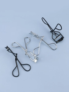 Close-up of four stainless steel eyelash curlers in black and silver finishes