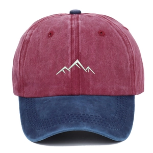 Detailed close-up of mountain embroidery on a washed burgundy and blue baseball cap