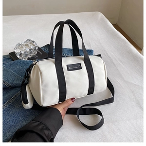 Detailed view of white nylon Boston bag with black straps and small zipper pouch