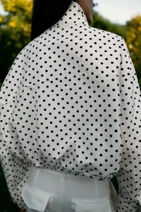 Detailansicht der Rückseite einer weißen Polka-Dot-Jacke mit elastischem Bund und Ärmeln
