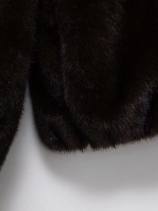 Detailed macro view of dark brown faux fur texture and stitching on the bomber jacket cuff