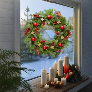Detail of Christmas wreath with pine needles, red berries, and stars on window glass