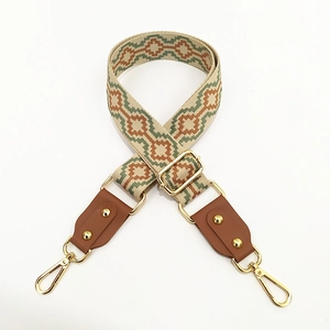 Close-up of geometric ethnic canvas strap with leather ends and golden metal hooks