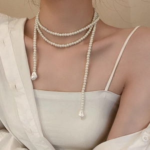 Détail d'un long collier de perles superposé avec des pendentifs en perles baroques
