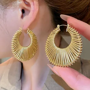 Boucles d'oreilles créoles dorées géométriques avec texture tissée et style vintage