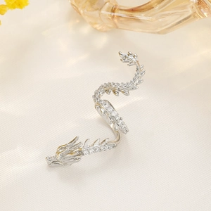 Makroaufnahme einer Drachen-Ohrmanschette in Silber mit Zirkonia auf weißer Seide