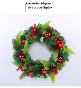 Detail of Christmas wreath with green pine needles, red berries, and pine cones