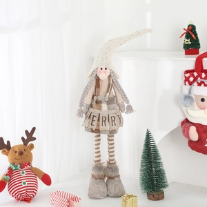 Detail of a plush Christmas gnome with white braids, patterned hat, and Merry apron