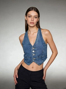 Close-up of blue washed denim vest featuring silver buttons and decorative front pockets