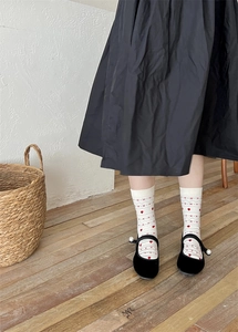 Détail de chaussettes en coton crème à motifs cœurs rouges avec chaussures à perles