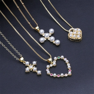 Close-up of four gold necklaces with pearl crosses and colorful gemstone heart pendants