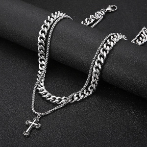 Detail of silver double-layered necklace with cuban chain and cross pendant on display