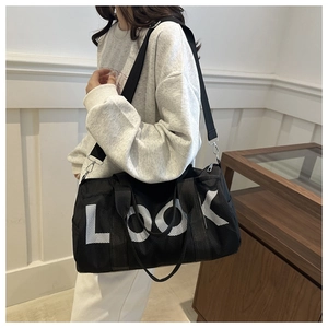 Detailed side view of black duffel travel bag with LOOK print worn by a model