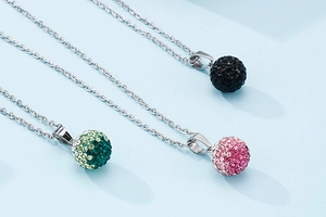 Close-up of sparkling rhinestone pavé ball pendants in black, green, and pink colors