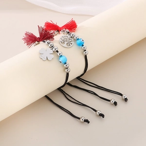 Detail of woven bracelets with evil eye beads and stainless steel tree charms